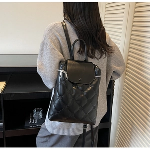 Close-up of black quilted leather backpack with metal buckle and adjustable straps