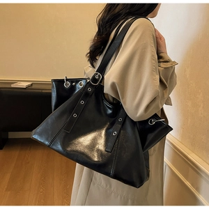 Close-up of vintage black tote bag with silver metal eyelets and adjustable strap