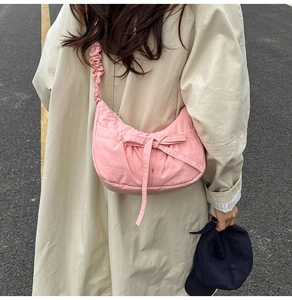 Detailed view of pink nylon crescent bag with drawstring strap and decorative bow