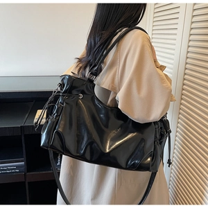 Detail of glossy black tote bag with side drawstring and metallic ring buckle