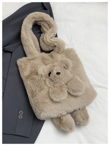 Detailed view of plush teddy bear shoulder bag on grey suit jacket background