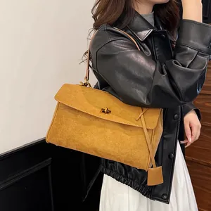 Détail du sac cabas en daim gingembre avec fermoir rotatif doré et étiquette assortie