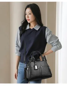 Close-up of black lychee textured Boston bag featuring silver hardware and dual handles