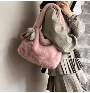 Detail of pink faux fur shoulder bag with soft plush texture and cute rabbit charm pendant