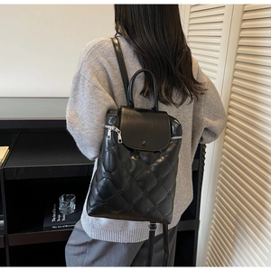 Detail of black quilted leather backpack with silver hardware on a casual model