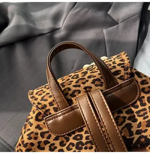 Detail of leopard print backpack showing brown leather handle and fine stitching craftsmanship