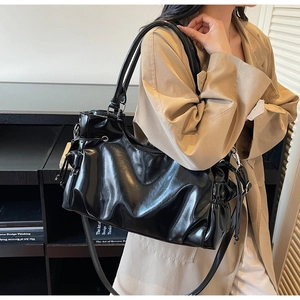 Detail of black glossy patent leather shoulder bag with side drawstring and ruched texture