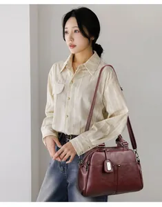 Detail showing deep red lychee pattern boston bag with metallic logo and sturdy handles
