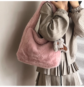 Detailed view of pink plush crossbody bag with a cute grey rabbit charm accessory