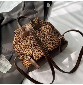 Detail of leopard print backpack with brown leather straps and metal buckle on grey suit