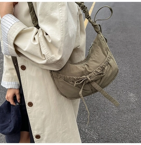 Detail of olive green nylon crescent bag featuring ruched strap and bow decoration