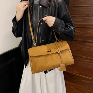 Sac cabas en daim marron avec fermoir doré porté à l'épaule par un mannequin