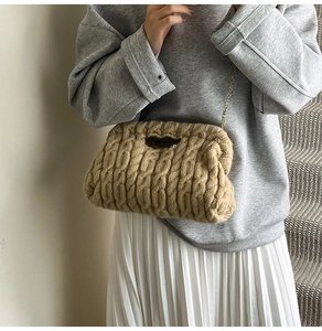 Close-up of knit texture and gold chain on camel knit handbag worn with pleated skirt