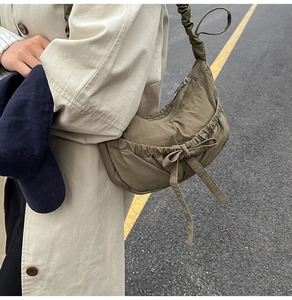 Detail of olive green nylon shoulder bag with pleated drawstring and knot decoration