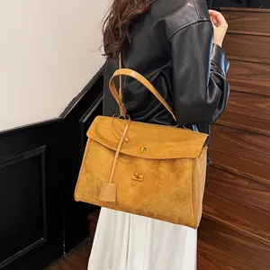 Détail d'un sac cabas en daim jaune avec fermoir doré sur fond d'escalier chic