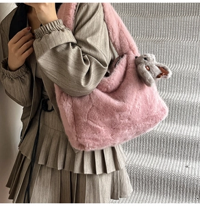 Pink plush tote bag detail with cute bunny charm on model in elegant brown outfit