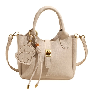 Elegant cream pebbled leather bucket bag with gold turn-lock and decorative dog charm