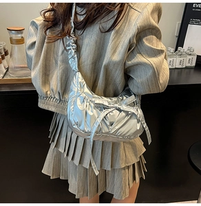 Metallic silver pleated crossbody bag with bow detail shown on model in cafe setting