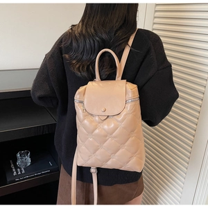 Model view of beige quilted backpack with elegant diamond pattern and top handle