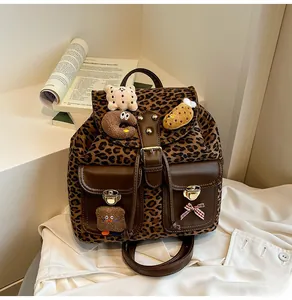 Detailed view of leopard print backpack with plush charms and textured leather pockets