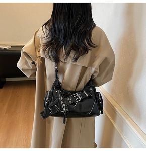 Détail du sac à bandoulière en cuir verni noir avec boucles décoratives et finitions argentées