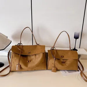 Comparaison de sacs cabas en daim marron, grand et petit modèles, avec boucles dorées