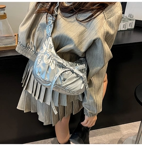 Detail of silver puffy quilted crossbody bag with stylish ribbon bow and metallic finish
