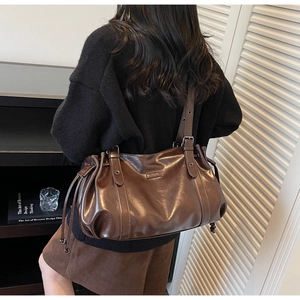 Détail du sac cabas marron foncé montrant les cordons latéraux et la texture cuir brillant
