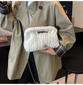 Detail of white chunky knit cloud bag with gold chain strap and textured weave pattern