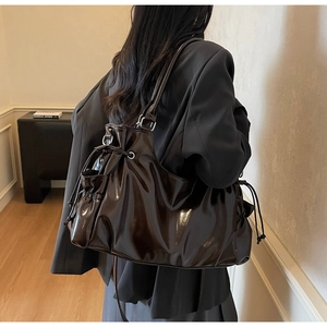 Detail of glossy coffee leather tote bag featuring drawstring closure and tassel accents