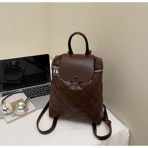 Detailed view of deep brown quilted backpack with elegant diamond pattern and metal zipper
