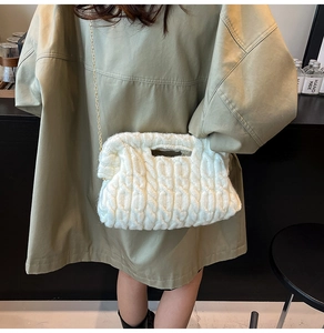 Close-up of white knitted crossbody bag featuring thick cable weave and gold chain strap
