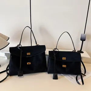 Détail de grands et petits sacs cabas en daim noir avec serrures carrées dorées rotatives