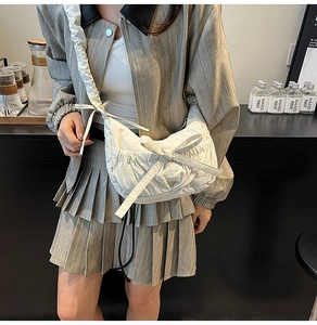 Detailed view of beige pleated crescent bag with large bow and wide shoulder strap