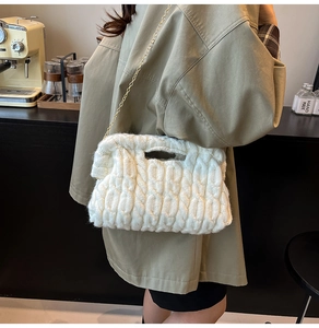 Close-up of white cable knit bag featuring thick yarn texture and golden chain strap