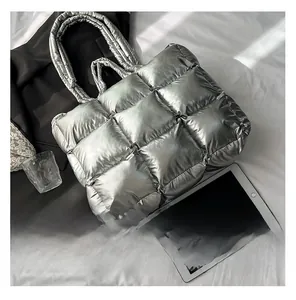 Close-up of metallic silver quilted tote bag showing large square stitching and dual handles
