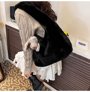 Close-up of a large black faux fur shoulder bag with plush bunny charm for autumn winter