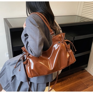 Close-up of caramel brown tote bag with side drawstrings and smooth polished finish