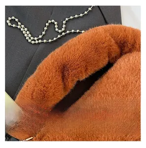 Close-up of fluffy orange faux fur handbag with stylish metal ball chain strap