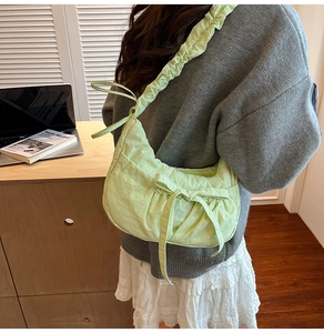 Detail of light green nylon crescent bag with ruched strap and bow decoration