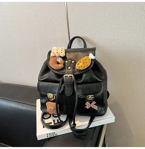 Close-up of black leather backpack featuring plush charms and gold metallic buckles