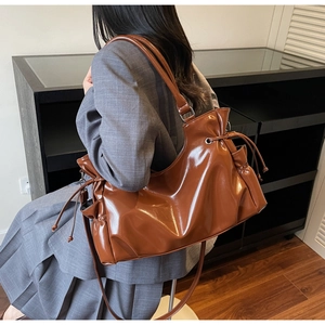Caramel hobo bag detail showing drawstring pleats and glossy faux leather texture