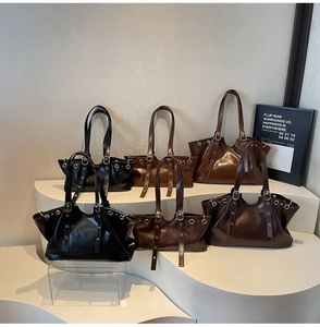 Detail view of vintage leather tote bags in various sizes with silver metal eyelets