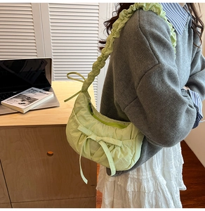 Detail of pistachio green pleated crossbody bag with bow drawstring and ruffled strap
