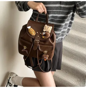 Detail of vintage brown leather backpack with cute plush charms and metal magnetic closures