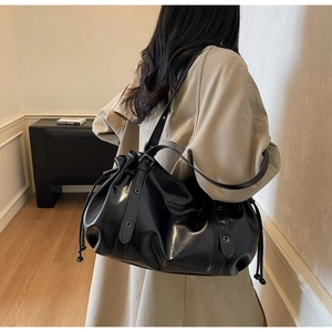 Vue détaillée d'un sac seau noir avec cordon de serrage en cuir brillant et œillets