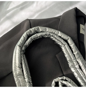 Close-up of quilted silver metallic shoulder strap with glossy finish on a tote bag