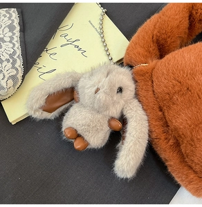 Gros plan d'un porte-clés lapin en peluche avec détails en cuir sur un sac à main doux