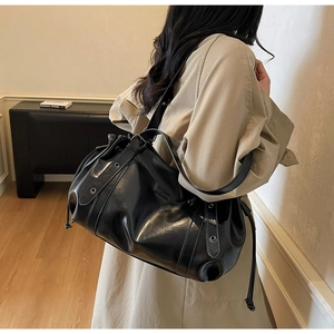 Détail du sac cabas en simili cuir noir brillant avec cordon et œillets argentés