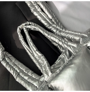 Close-up of metallic silver quilted tote bag handles with wide padded stitching detail